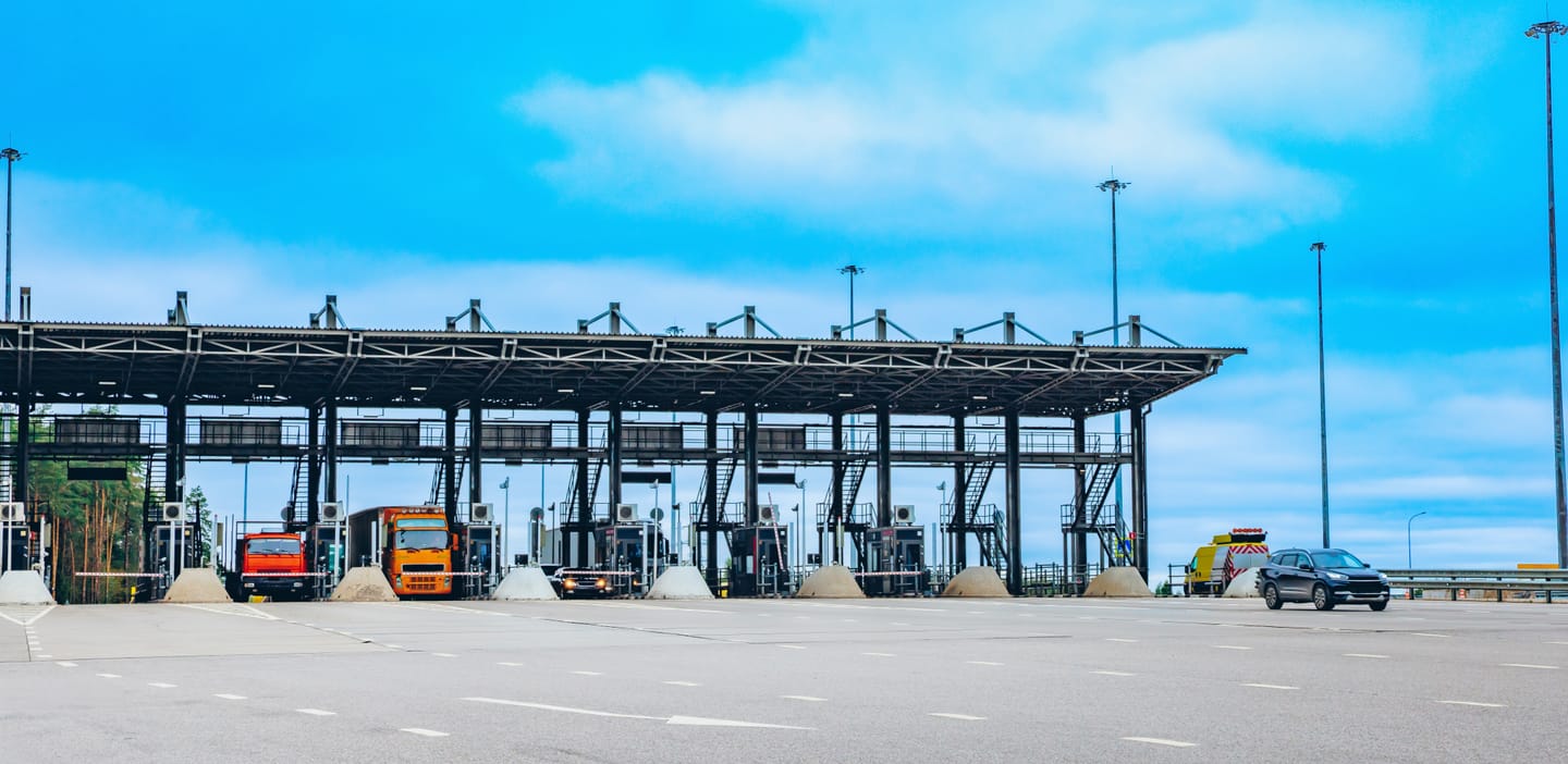 Lastbiler ved en betalingsstation på motorvejen.