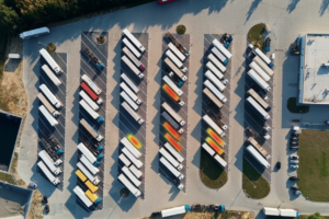 Aerial view of a truck park with rows of parked lorries and coloured occupancy highlights on several spaces.633694d79440 2026 05 14